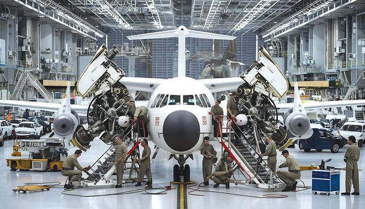 Airplane assembly in a large hangar with workers and equipment