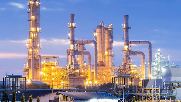 Industrial refinery at dusk, showcasing complex piping and illuminated structures.