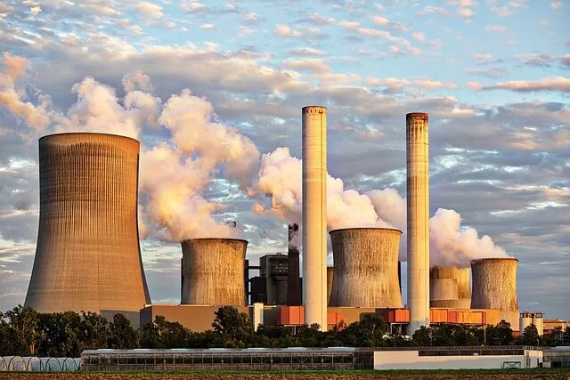 Industrial power plant with cooling towers emitting steam, a symbol of energy production.
