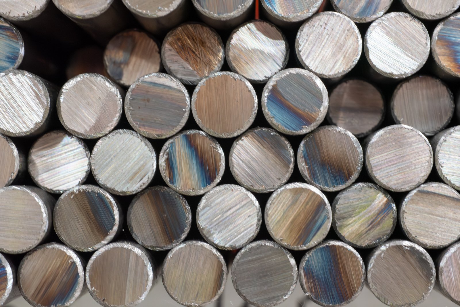 Close-up of stacked Monel metal rods with varied, iridescent finishes.